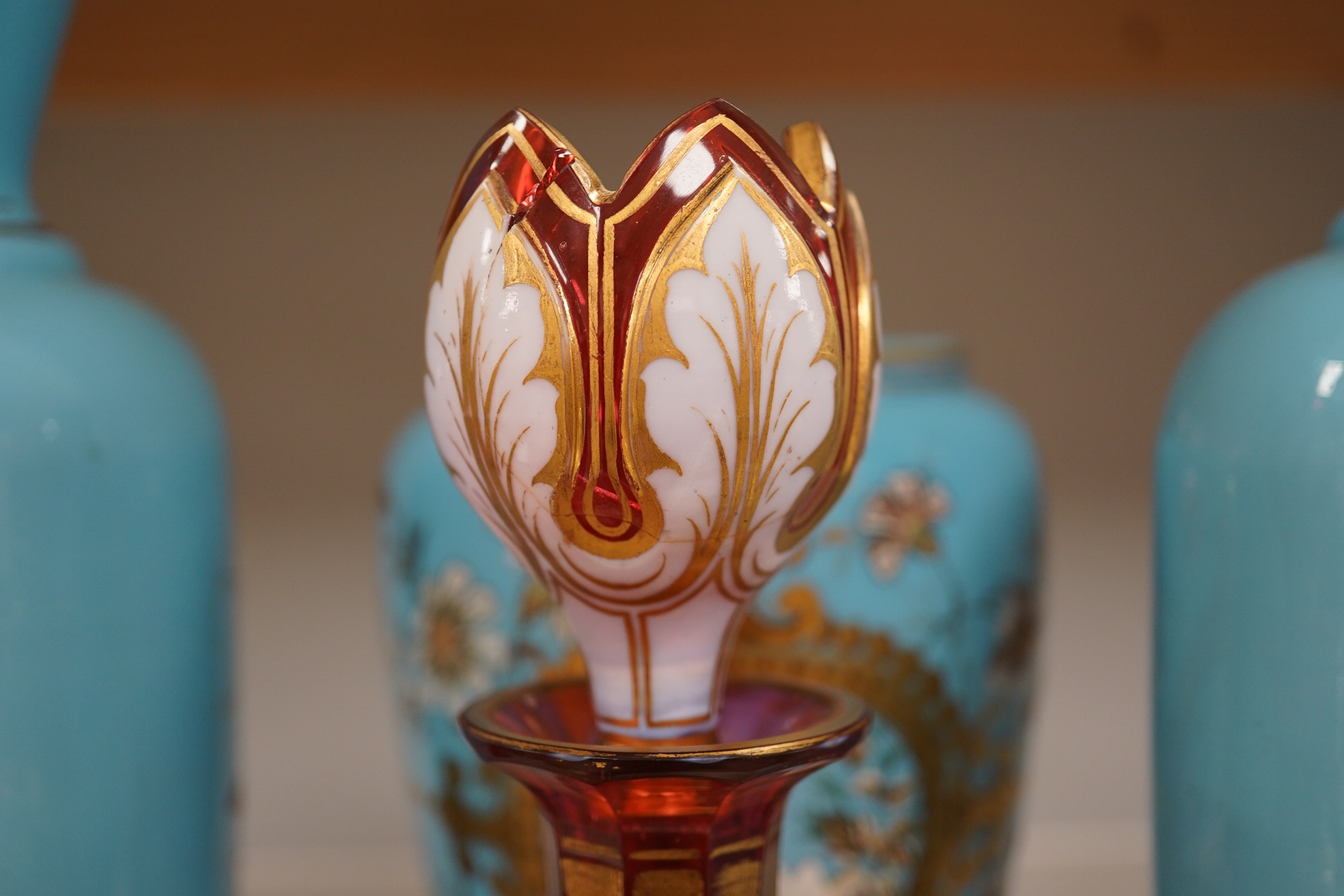 An enamelled glass garniture decorated with Egyptian scenes and a cranberry decanter, largest 29cm high. Condition - poor to fair